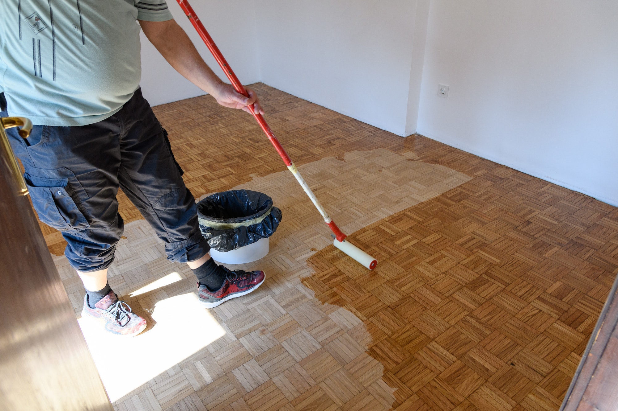 Man applying lacquer finish on oak hardwood floor