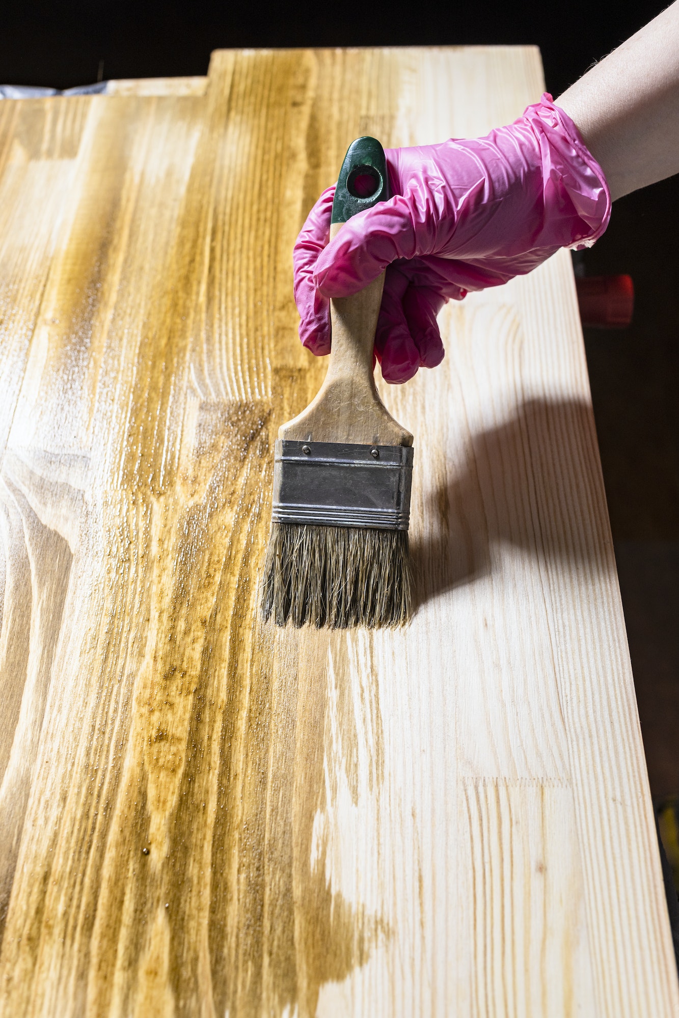 solid board is hued with wood stain by paintbrush